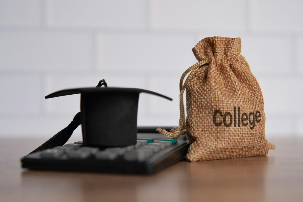 Closeup image of graduation cap, calculator and money bag with word COLLEGE.