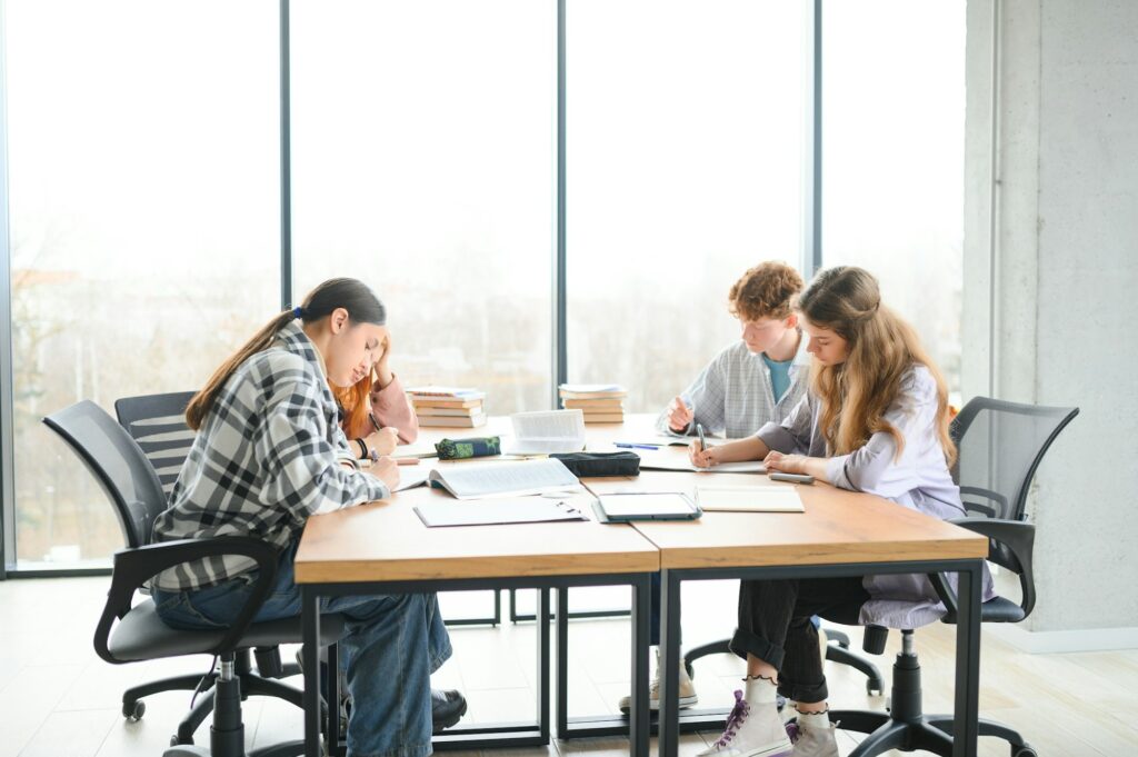 Happy group of friendly students talking, discussing new school project ideas together