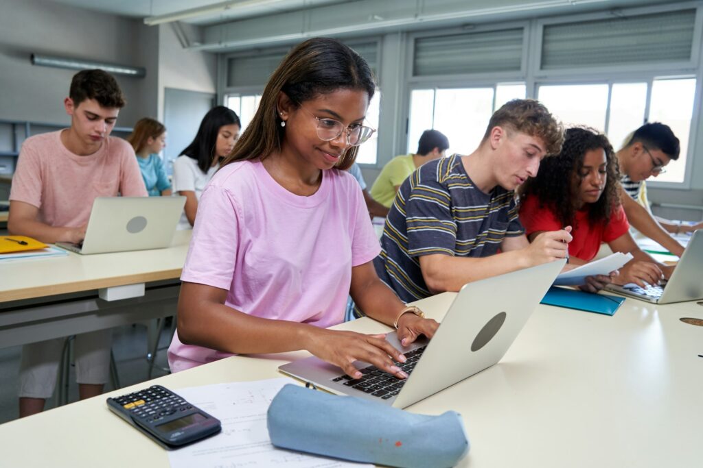 International students in class using laptop to work, concentrated studying with cheerful face.