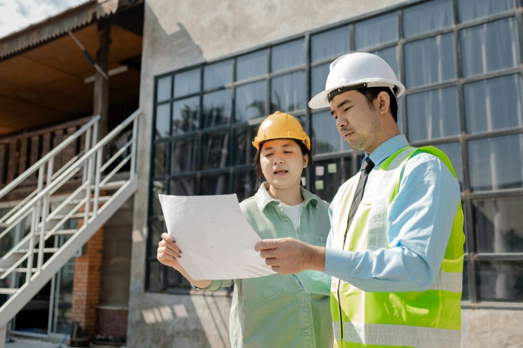 Smart civil architect engineer inspecting and working outdoors structure building site with blueprin