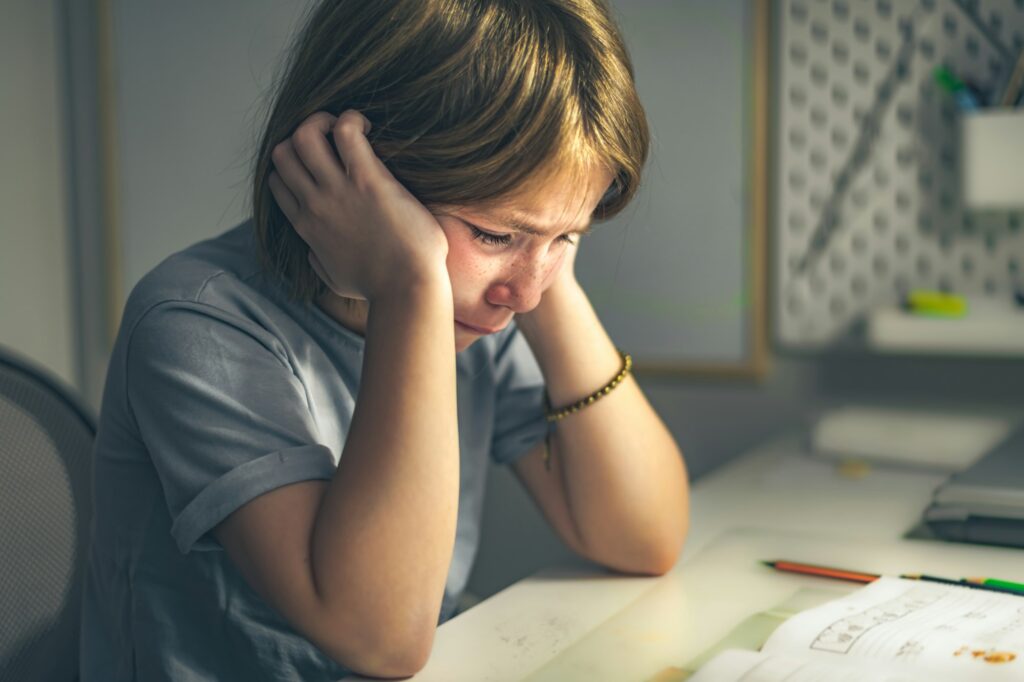 upset schoolgirl doing lessons, her homework. learning difficulties